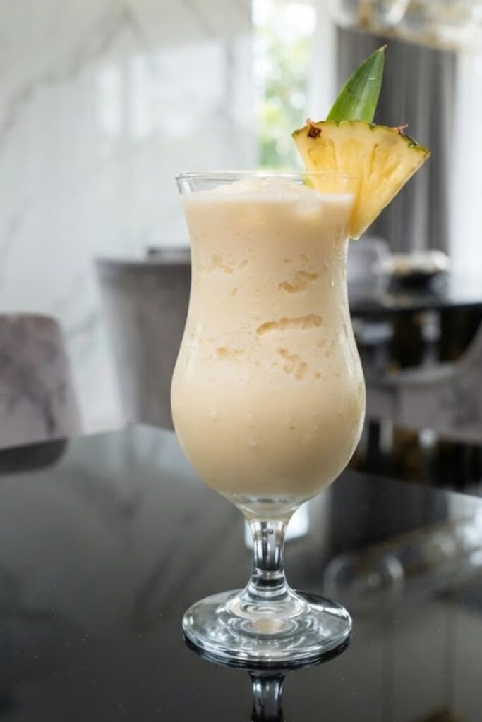Creamy virgin piña colada made with pineapple juice, coconut milk, crushed ice, and fresh pineapple garnish